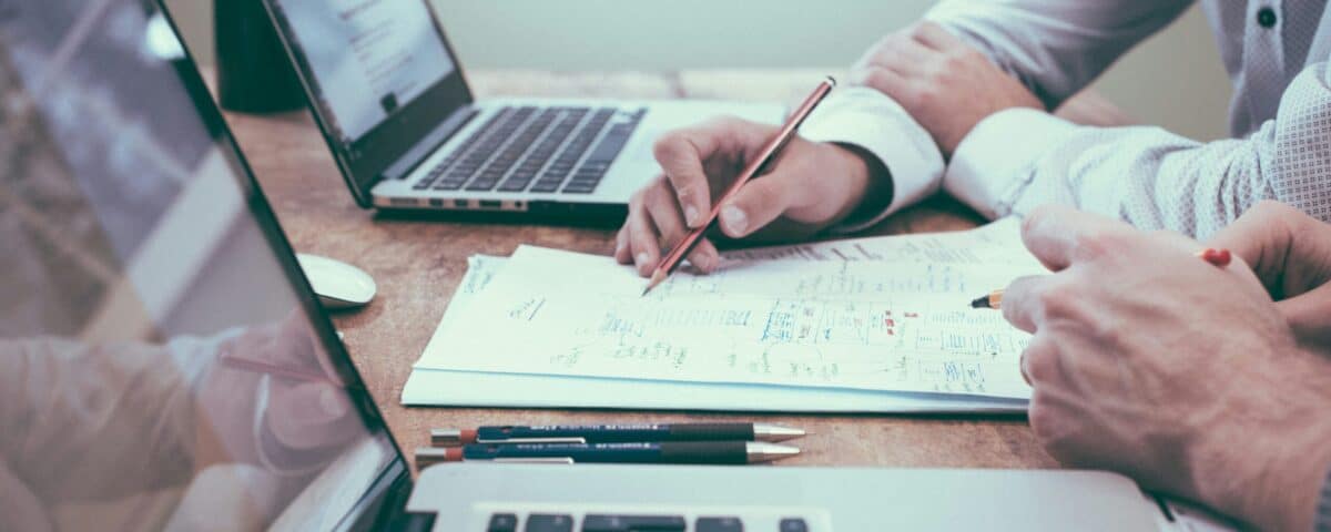 person holding a pencil near laptop