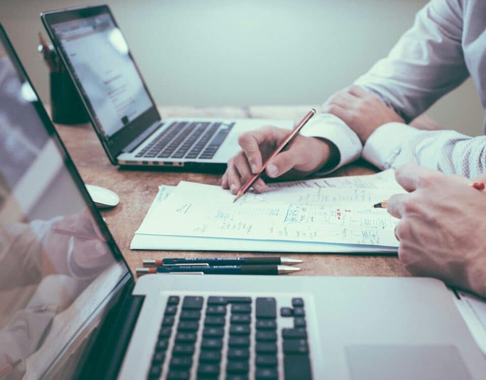 person holding a pencil near laptop