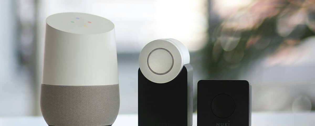 white and gray Google smart speaker and wo black speakers